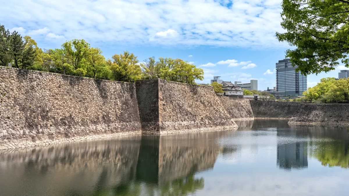 水辺に映る大阪城石垣と青空とビルの風景