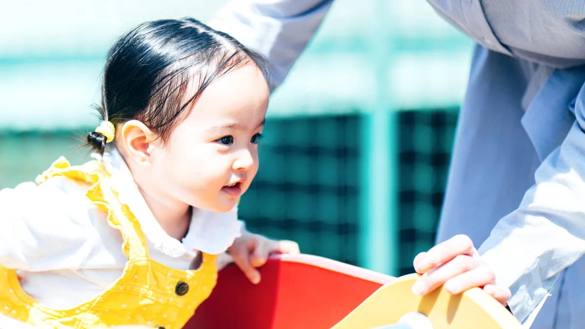 公園の滑り台で遊ぶ幼児と母親